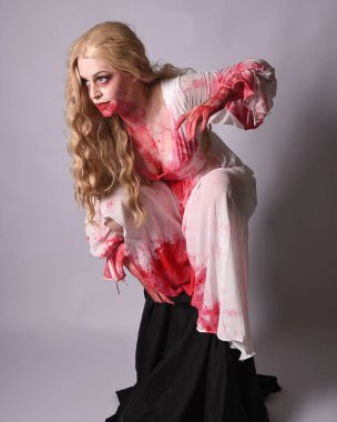  Korkunç vampir zombi gelinin portresi. Cadılar bayramı fantezi kostümü giymiş. Üzerinde kanlı kırmızı boya lekeleri var. Stüdyo arka planında izole edilmiş 