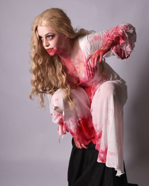  Korkunç vampir zombi gelinin portresi. Cadılar bayramı fantezi kostümü giymiş. Üzerinde kanlı kırmızı boya lekeleri var. Stüdyo arka planında izole edilmiş 