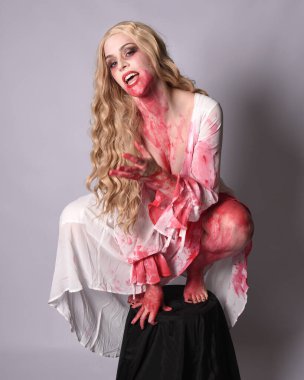  Korkunç vampir zombi gelinin portresi. Cadılar bayramı fantezi kostümü giymiş. Üzerinde kanlı kırmızı boya lekeleri var. Stüdyo arka planında izole edilmiş 