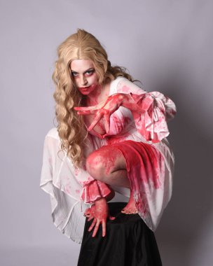  Korkunç vampir zombi gelinin portresi. Cadılar bayramı fantezi kostümü giymiş. Üzerinde kanlı kırmızı boya lekeleri var. Stüdyo arka planında izole edilmiş 