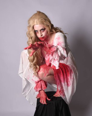  Korkunç vampir zombi gelinin portresi. Cadılar bayramı fantezi kostümü giymiş. Üzerinde kanlı kırmızı boya lekeleri var. Stüdyo arka planında izole edilmiş 