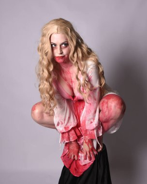  Korkunç vampir zombi gelinin portresi. Cadılar bayramı fantezi kostümü giymiş. Üzerinde kanlı kırmızı boya lekeleri var. Stüdyo arka planında izole edilmiş 