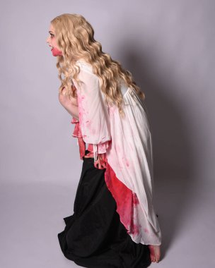  Korkunç vampir zombi gelinin portresi. Cadılar bayramı fantezi kostümü giymiş. Üzerinde kanlı kırmızı boya lekeleri var. Stüdyo arka planında izole edilmiş 