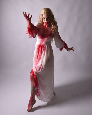  Korkunç vampir zombi gelinin portresi. Üzerinde kanlı kırmızı boya lekeleri olan şık bir Cadılar Bayramı fantazisi kostümü var. Elinde şarap kadehi var. Stüdyo arka planında izole edilmiş 
