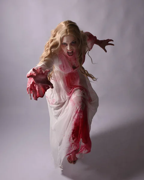 stock image  Full length portrait of  scary vampire zombie bride, wearing elegant halloween fantasy costume  dress with bloody red paint splatter. in standing walking pose. Isolated on studio background 