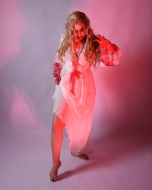 Cadılar bayramı fantezi elbisesi giymiş korkunç vampir gelin portresi. Dinamik atlama, hareketli kollar uzanıyor. Sinema kırmızı ışıklandırmalı izole stüdyo arkaplanı.