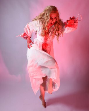 Cadılar bayramı fantezi elbisesi giymiş korkunç vampir gelin portresi. Dinamik atlama, hareketli kollar uzanıyor. Sinema kırmızı ışıklandırmalı izole stüdyo arkaplanı.