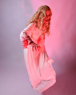 Cadılar bayramı fantezi elbisesi giymiş korkunç vampir gelin portresi. Dinamik atlama, hareketli kollar uzanıyor. Sinema kırmızı ışıklandırmalı izole stüdyo arkaplanı.