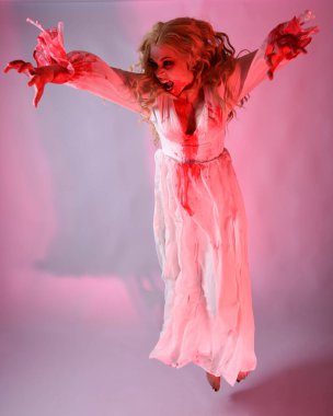 Cadılar bayramı fantezi elbisesi giymiş korkunç vampir gelin portresi. Dinamik atlama, hareketli kollar uzanıyor. Sinema kırmızı ışıklandırmalı izole stüdyo arkaplanı.