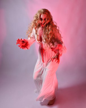 Cadılar bayramı fantezi elbisesi giymiş korkunç vampir gelin portresi. Dinamik atlama, hareketli kollar uzanıyor. Sinema kırmızı ışıklandırmalı izole stüdyo arkaplanı.