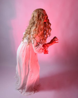 Cadılar bayramı fantezi elbisesi giymiş korkunç vampir gelin portresi. Dinamik atlama, hareketli kollar uzanıyor. Sinema kırmızı ışıklandırmalı izole stüdyo arkaplanı.