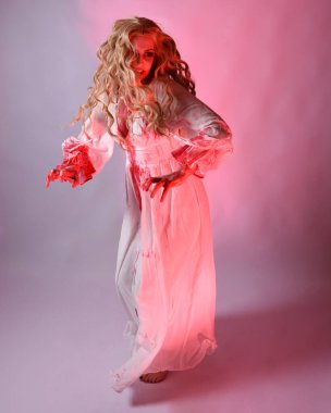 Cadılar bayramı fantezi elbisesi giymiş korkunç vampir gelin portresi. Dinamik atlama, hareketli kollar uzanıyor. Sinema kırmızı ışıklandırmalı izole stüdyo arkaplanı.