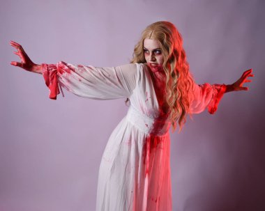 Korkunç vampir gelinin, şık cadılar bayramı fantezi kostümlü, kanlı sıçrayan portresi. Stüdyonun arka planında el hareketleriyle kameraya uzanan izole bir şekilde..