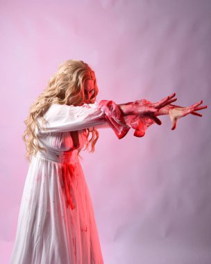 Korkunç vampir gelinin, şık cadılar bayramı fantezi kostümlü, kanlı sıçrayan portresi. Stüdyonun arka planında el hareketleriyle kameraya uzanan izole bir şekilde..