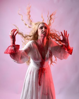 Korkunç vampir gelinin, şık cadılar bayramı fantezi kostümlü, kanlı sıçrayan portresi. Stüdyonun arka planında el hareketleriyle kameraya uzanan izole bir şekilde..