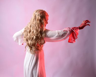 Korkunç vampir gelinin, şık cadılar bayramı fantezi kostümlü, kanlı sıçrayan portresi. Stüdyonun arka planında el hareketleriyle kameraya uzanan izole bir şekilde..