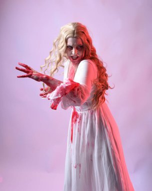 Korkunç vampir gelinin, şık cadılar bayramı fantezi kostümlü, kanlı sıçrayan portresi. Stüdyonun arka planında el hareketleriyle kameraya uzanan izole bir şekilde..