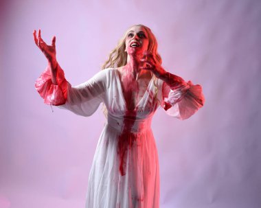 Korkunç vampir gelinin, şık cadılar bayramı fantezi kostümlü, kanlı sıçrayan portresi. Stüdyonun arka planında el hareketleriyle kameraya uzanan izole bir şekilde..