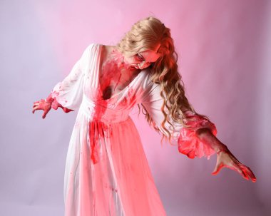 Korkunç vampir gelinin, şık cadılar bayramı fantezi kostümlü, kanlı sıçrayan portresi. Stüdyonun arka planında el hareketleriyle kameraya uzanan izole bir şekilde..