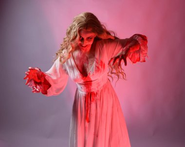 Korkunç vampir gelinin, şık cadılar bayramı fantezi kostümlü, kanlı sıçrayan portresi. Stüdyonun arka planında el hareketleriyle kameraya uzanan izole bir şekilde..