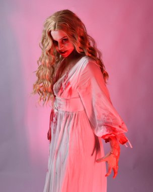 Korkunç vampir gelinin, şık cadılar bayramı fantezi kostümlü, kanlı sıçrayan portresi. Stüdyonun arka planında el hareketleriyle kameraya uzanan izole bir şekilde..