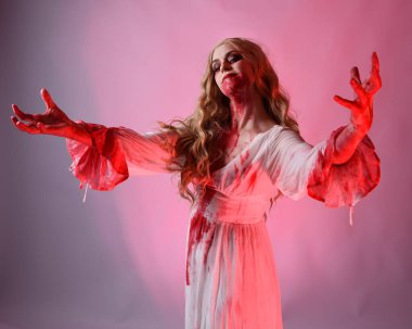 Korkunç vampir gelinin, şık cadılar bayramı fantezi kostümlü, kanlı sıçrayan portresi. Stüdyonun arka planında el hareketleriyle kameraya uzanan izole bir şekilde..