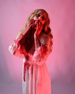 Korkunç vampir gelinin, şık cadılar bayramı fantezi kostümlü, kanlı sıçrayan portresi. Stüdyonun arka planında el hareketleriyle kameraya uzanan izole bir şekilde..