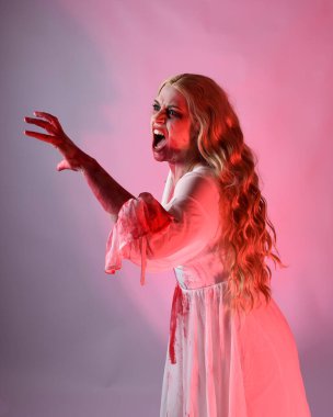 Korkunç vampir gelinin, şık cadılar bayramı fantezi kostümlü, kanlı sıçrayan portresi. Stüdyonun arka planında el hareketleriyle kameraya uzanan izole bir şekilde..