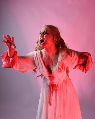 Korkunç vampir gelinin, şık cadılar bayramı fantezi kostümlü, kanlı sıçrayan portresi. Stüdyonun arka planında el hareketleriyle kameraya uzanan izole bir şekilde..