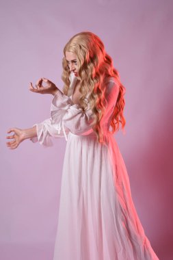 Zarif beyaz cadılar bayramı elbisesi giyen güzel sarışın mankenin yakın portresi. Aç vampir gibi uzanan kollar. Kırmızı karamsar ışıklandırma ile stüdyo arka planında izole.