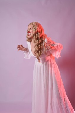 Zarif beyaz cadılar bayramı elbisesi giyen güzel sarışın mankenin yakın portresi. Aç vampir gibi uzanan kollar. Kırmızı karamsar ışıklandırma ile stüdyo arka planında izole.