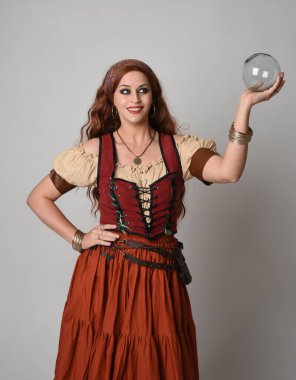 close up portrait of beautiful red haired woman wearing a medieval maiden, fortune teller costume. Posing while  holding a  crystal ball. isolated on studio background. clipart