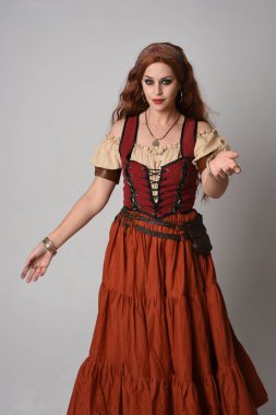 close up portrait of beautiful red haired woman wearing a medieval maiden, fortune teller costume. Posing with gestural hands reaching out, dancing, isolated on studio background. clipart