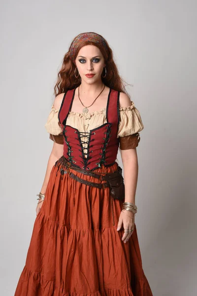 stock image close up portrait of beautiful red haired woman wearing a medieval maiden, fortune teller costume. Posing with gestural hands reaching out, dancing, isolated on studio background.