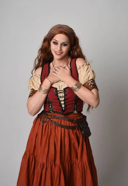 stock image close up portrait of beautiful red haired woman wearing a medieval maiden, fortune teller costume. Posing with gestural hands reaching out, dancing, isolated on studio background.