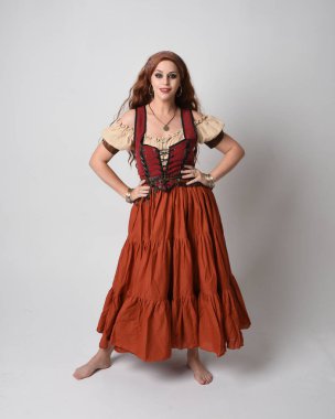 Full length portrait of beautiful red haired woman wearing a medieval maiden, fortune teller costume. Standing pose with dancing gestures, twirling skirt. isolated on studio background. clipart
