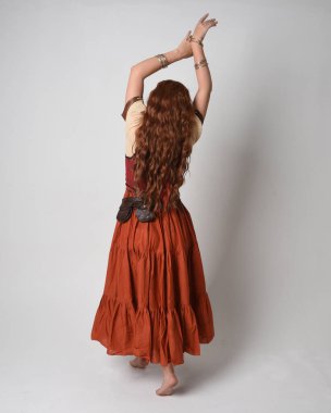 Full length portrait of beautiful red haired woman wearing a medieval maiden, fortune teller costume. Standing pose back view, walking away. isolated on studio background. clipart