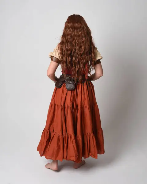 stock image Full length portrait of beautiful red haired woman wearing a medieval maiden, fortune teller costume. Standing pose back view, walking away. isolated on studio background.