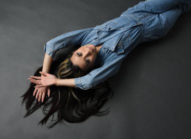 Esmer kadın Asyalı modelin günlük giysiler ve çift kot pantolon giymiş tam boy portresi. Karanlık stüdyo arka planında gölgelerle izole edilmiş.