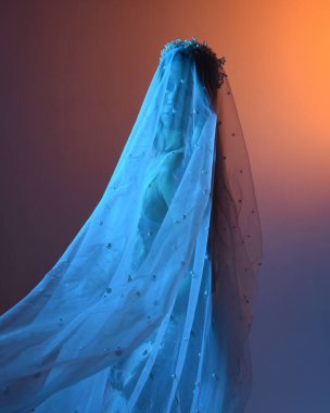 Beyaz gelinlik giymiş güzel bir mankenin yakın portresi ve kefen gibi akan bir duvak. Huysuz sinematik ışıklandırma, karanlık bir stüdyonun arka planında izole edilmiş..