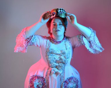  Zengin pembe bir elbise giyen kadın modelin portresi, tarihi bir Fransız barok asaleti kostümü, Marie Antoinette tarzı. Stüdyo arka planında izole edilmiş sinematik renkli ışıklandırma