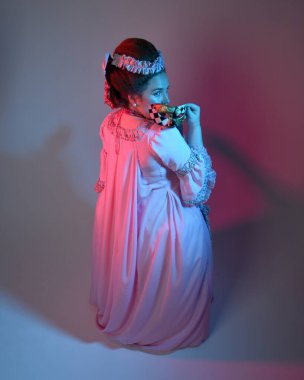  Zengin pembe bir elbise giyen kadın modelin portresi, tarihi bir Fransız barok asaleti kostümü, Marie Antoinette tarzı. Stüdyo arka planında izole edilmiş sinematik renkli ışıklandırma