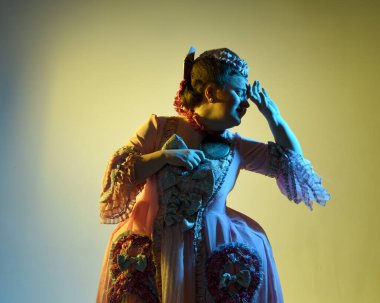  Gösterişli pembe bir elbise giyen kadın modelin sinematik portresi, tarihi bir Fransız barok asaleti kostümü, Marie Antoinette tarzı. Stüdyonun arka planında el aynası var..