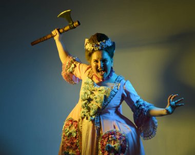 Gösterişli pembe bir elbise giyen kadın modelin portresi, tarihi bir Fransız barok asilzadesi kostümü, Marie Antoinette tarzı. Elinde balta ile devrimci saldırı pozisyonu tutuyordu. stüdyo arka planı