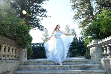 Peri masalı elf prensesi gibi mavi fantezi balo elbisesi giyen güzel bir kadın modelin portresi. Merdivenlerde, romantik bir şatonun balkonunun merdivenlerinde yürüyorum..
