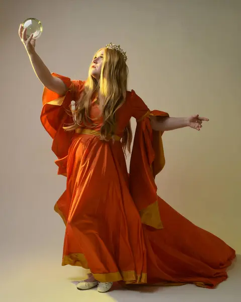 stock image Full length portrait of plus sized woman blonde hair, wearing historical medieval fantasy gown, golden crown of royal queen. Standing pose holding crystal seer orb, isolated studio background.