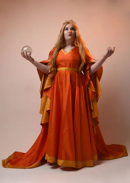 stock image Full length portrait of plus sized woman blonde hair, wearing historical medieval fantasy gown, golden crown of royal queen. Standing pose holding crystal seer orb, isolated studio background.