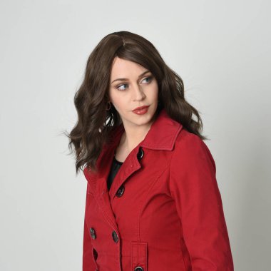 Kafası ve omuzları, güzel esmer kadın modelinin kırmızı yağmurluk giymiş portresini kapatıyor. anlamlı duygusal yüz ifadeleri, gülümseme. Beyaz stüdyo arka planında izole.