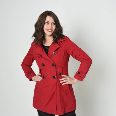 Kafası ve omuzları, güzel esmer kadın modelinin kırmızı yağmurluk giymiş portresini kapatıyor. Beyaz stüdyo arka planında izole