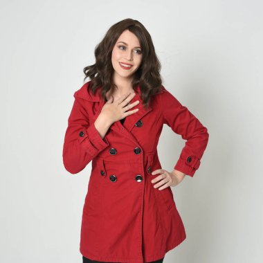 Kafası ve omuzları, güzel esmer kadın modelinin kırmızı yağmurluk giymiş portresini kapatıyor. Beyaz stüdyo arka planında izole